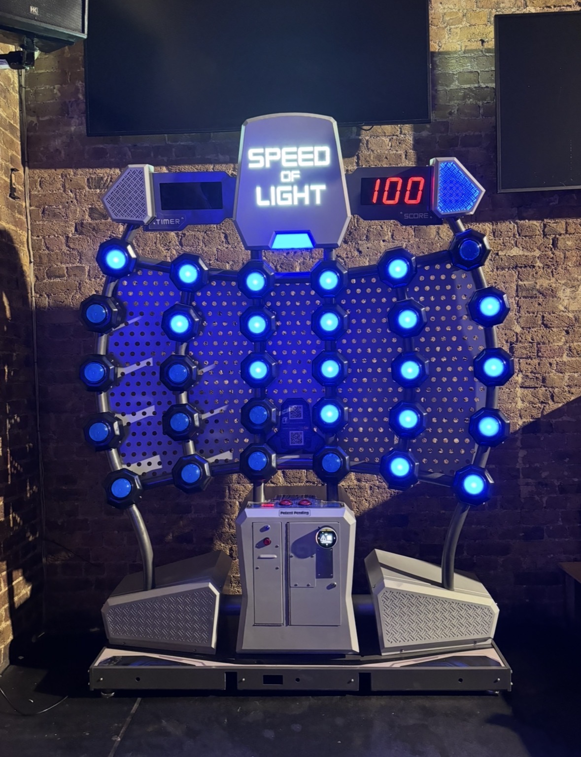 Interactive light wall titled 'Speed of Light' with blue illuminated hexagonal nodes and a red score display showing 100 on the right.
